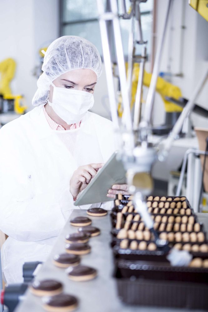 Woman in factory using tablet with robot handling cookies
